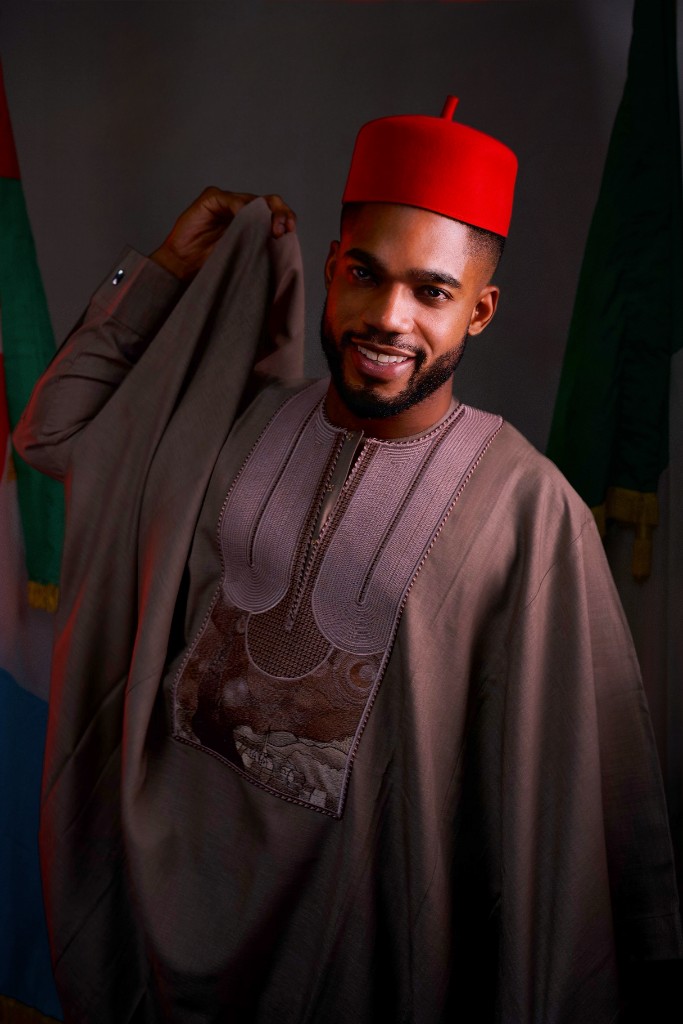 Osborn Nweze Umahi smiling in a taupe agbada and red cap, lifting the robe.