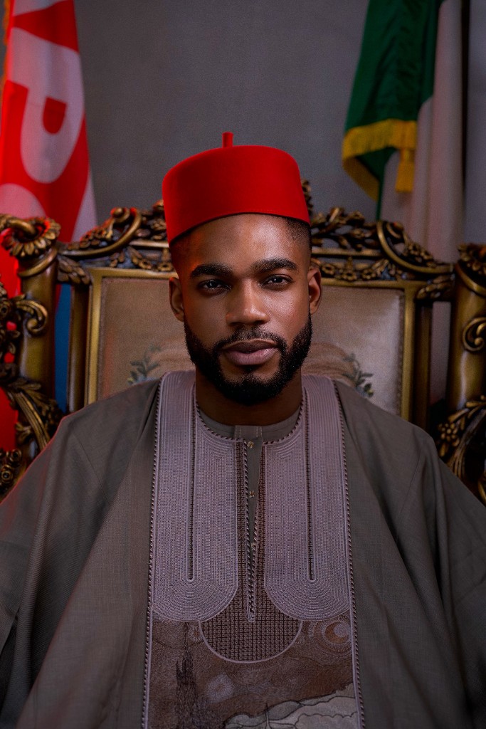 A closer portrait of Osborn Nweze Umahi seated in a taupe agbada and red cap.