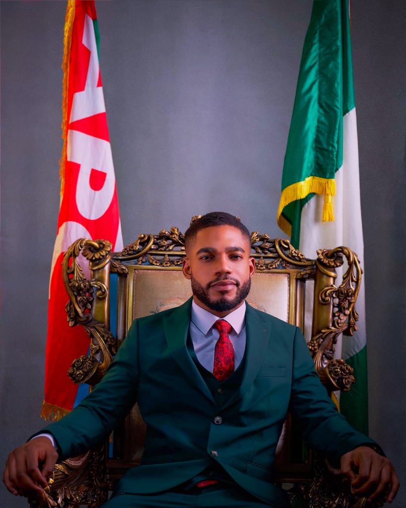 Osborn Nweze Umahi seated in a green suit, with the Ebonyi and Nigerian flags behind him.